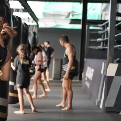 A student drives a knee into the heavy bag during a Muay Thai class