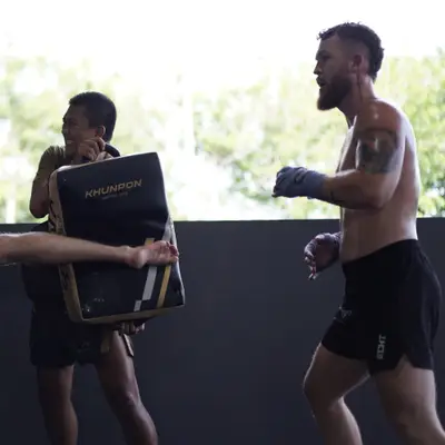 A Thai trainer holds the kick shield for a roundhouse kick