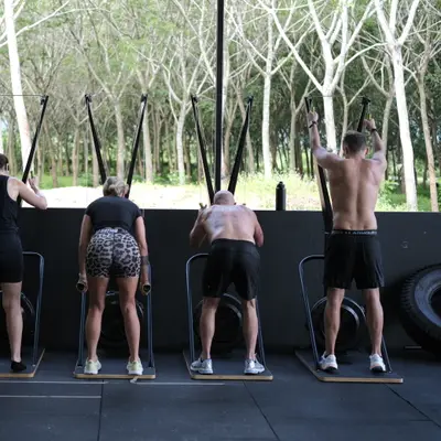 A row of members on the SkiErgs facing the trees