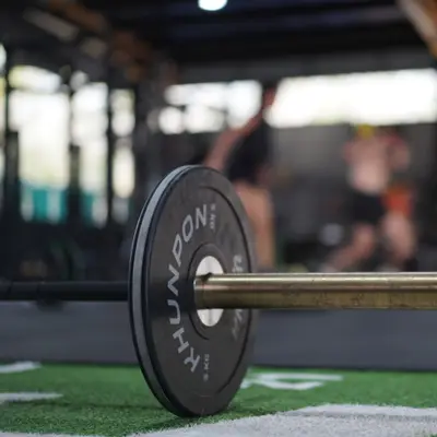 A Khunpon plate on a barbell with the class working behind it