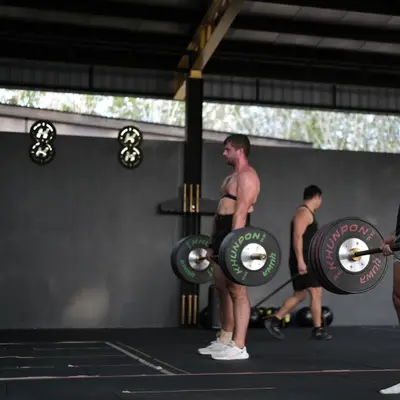 Two members deadlift Khunpon barbells side by side