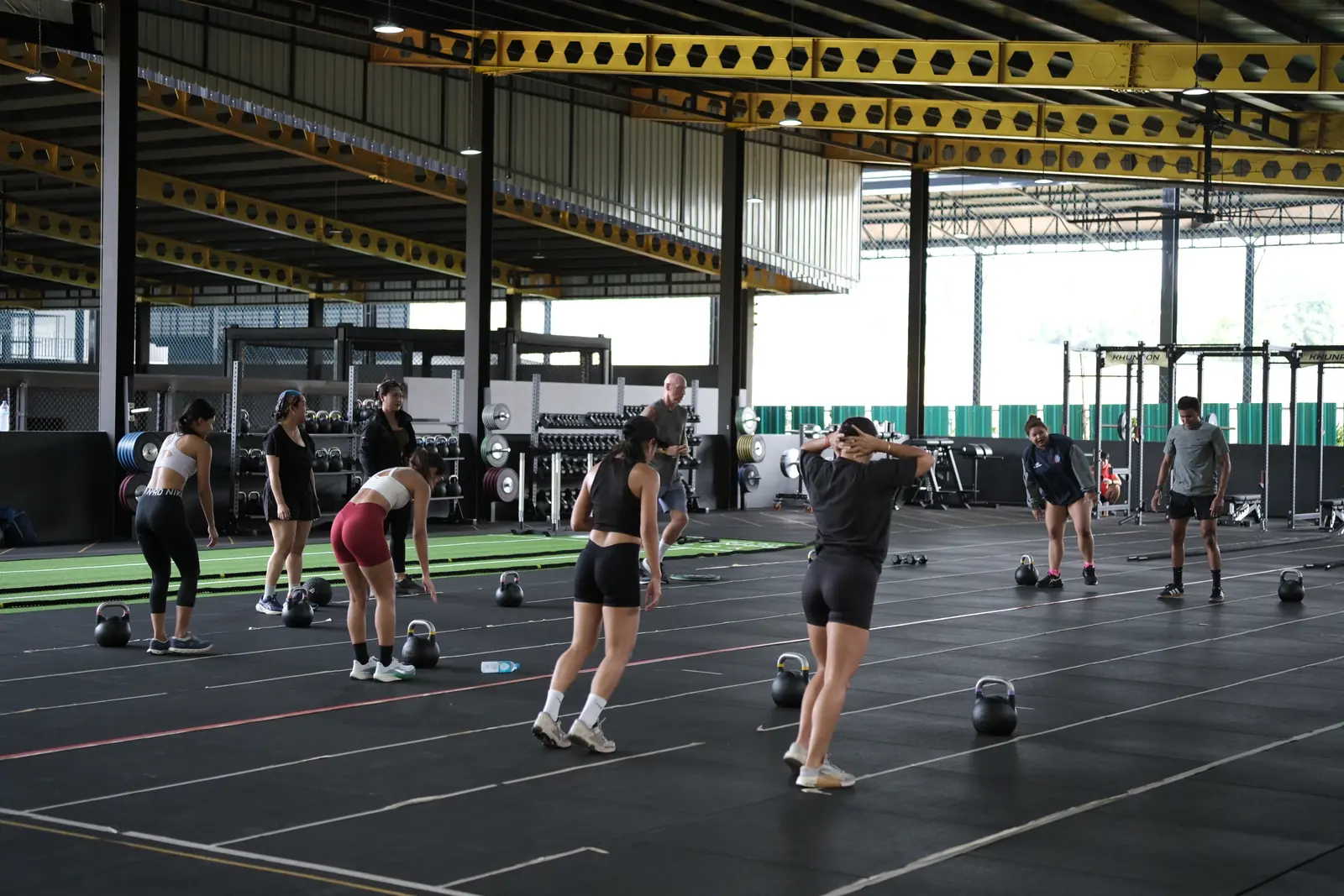 A strength and conditioning class spread across the floor with kettlebells