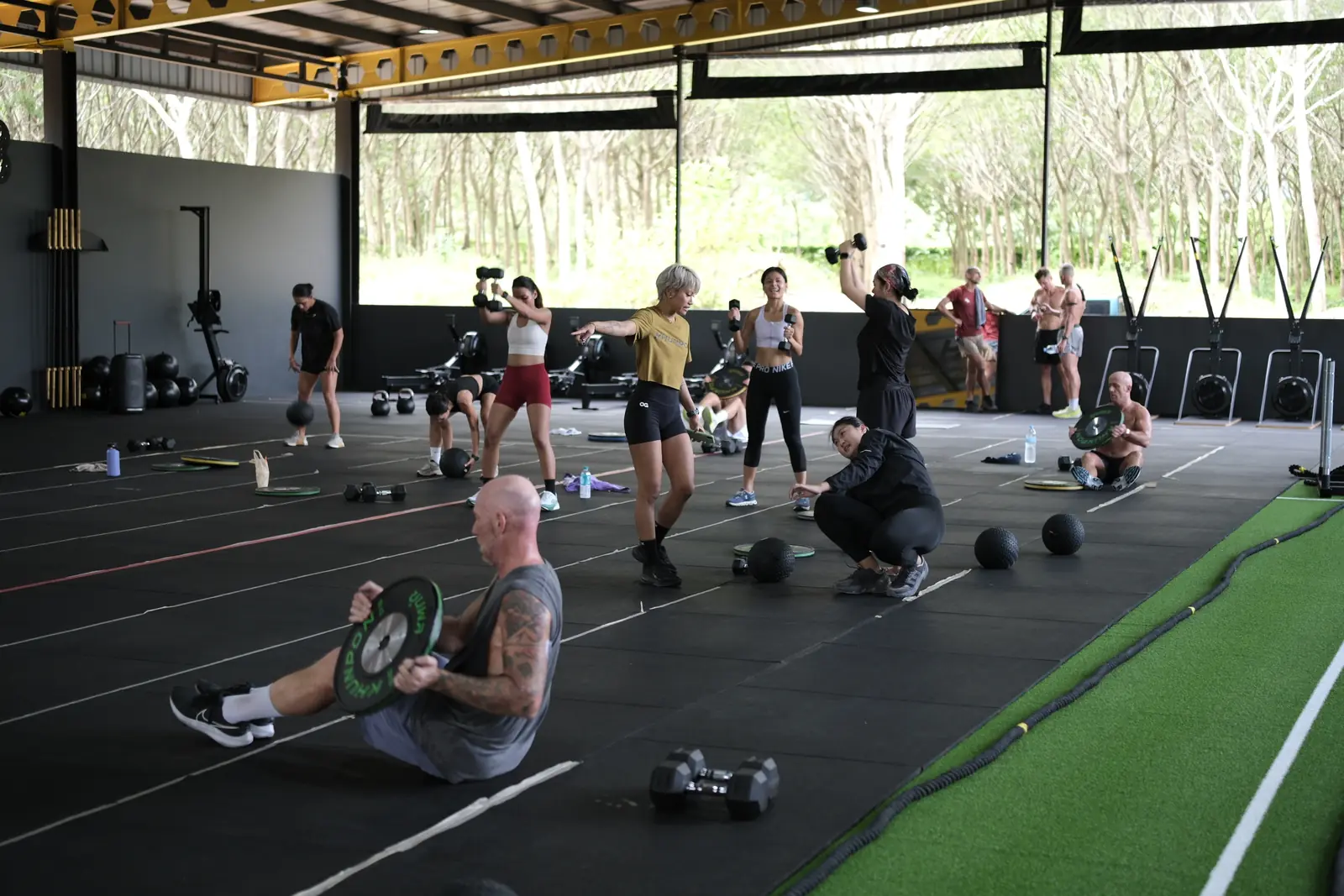 A member presses a weight plate from the floor in a circuit class