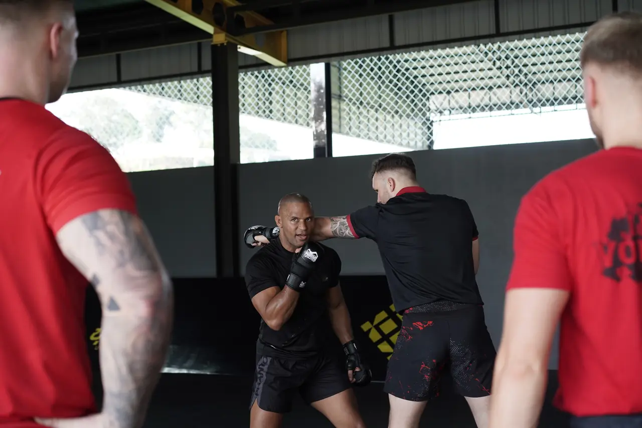 The head coach shows a fighter a clinch position during an MMA session at Khunpon