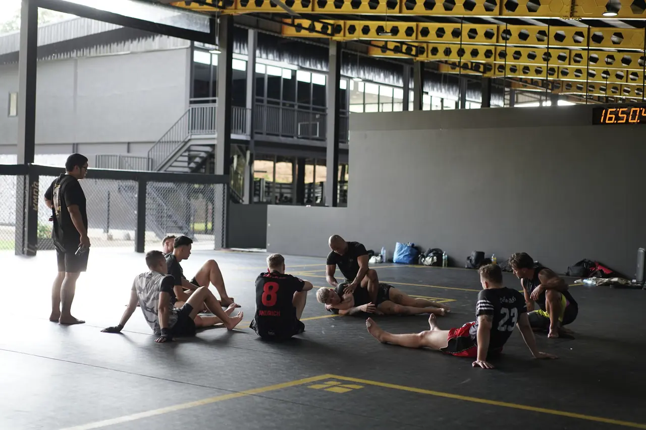 Fighters rest and drill ground work on the mats after an MMA session at Khunpon